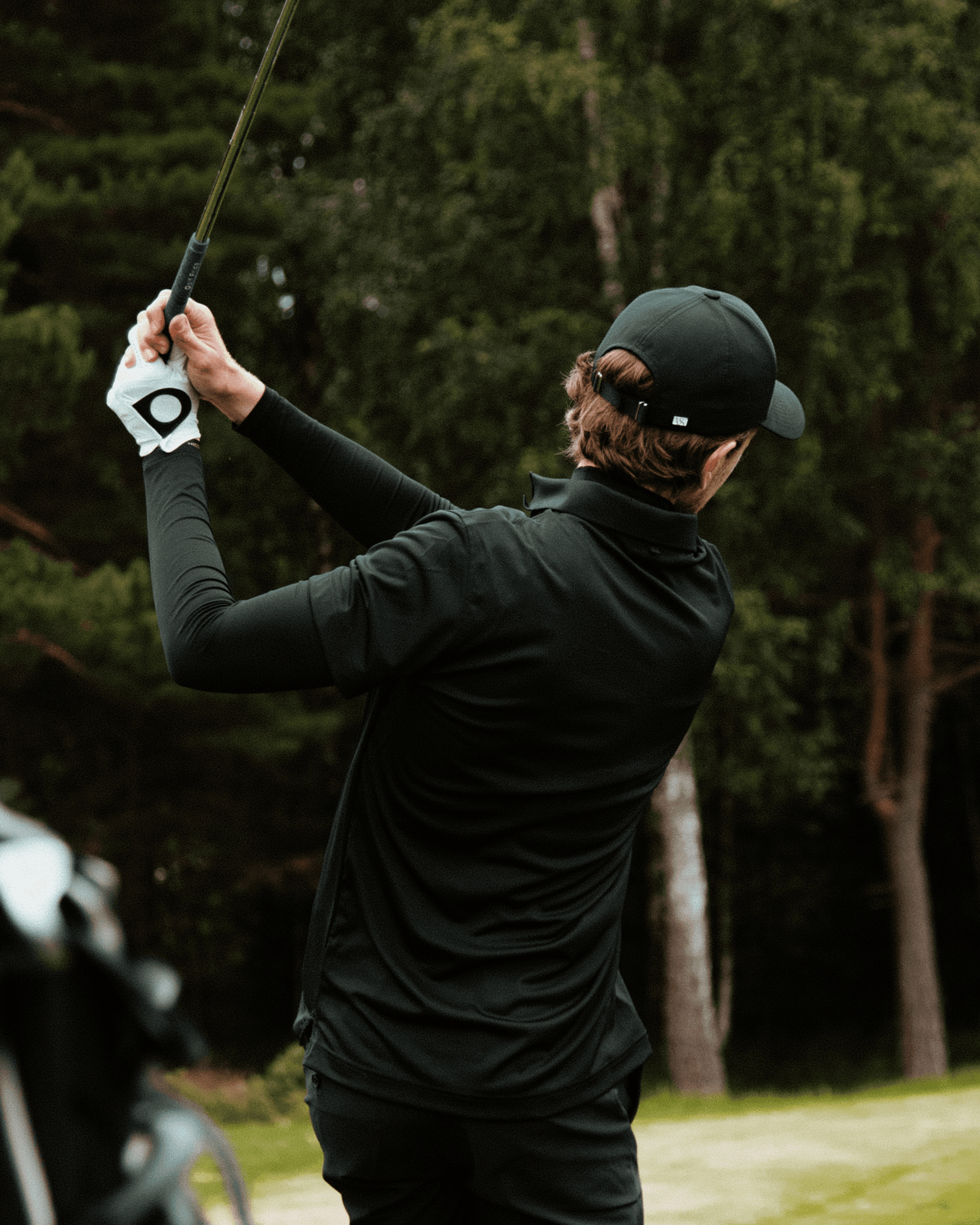 back view of a golfer wearing a black athletic sport cap on golf course