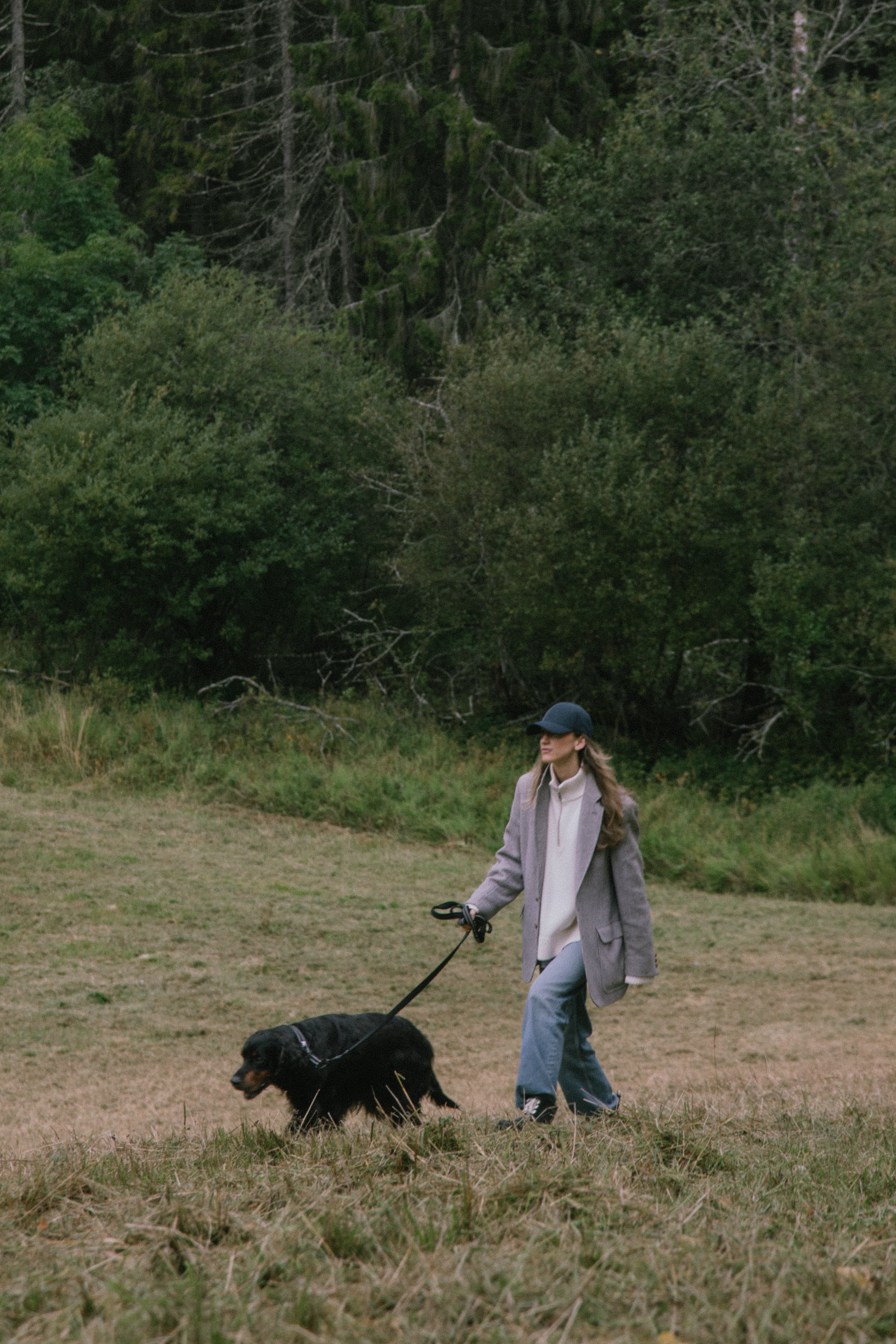 Female walking dog in woods in Norway wearing a navy cap from varsity headwear