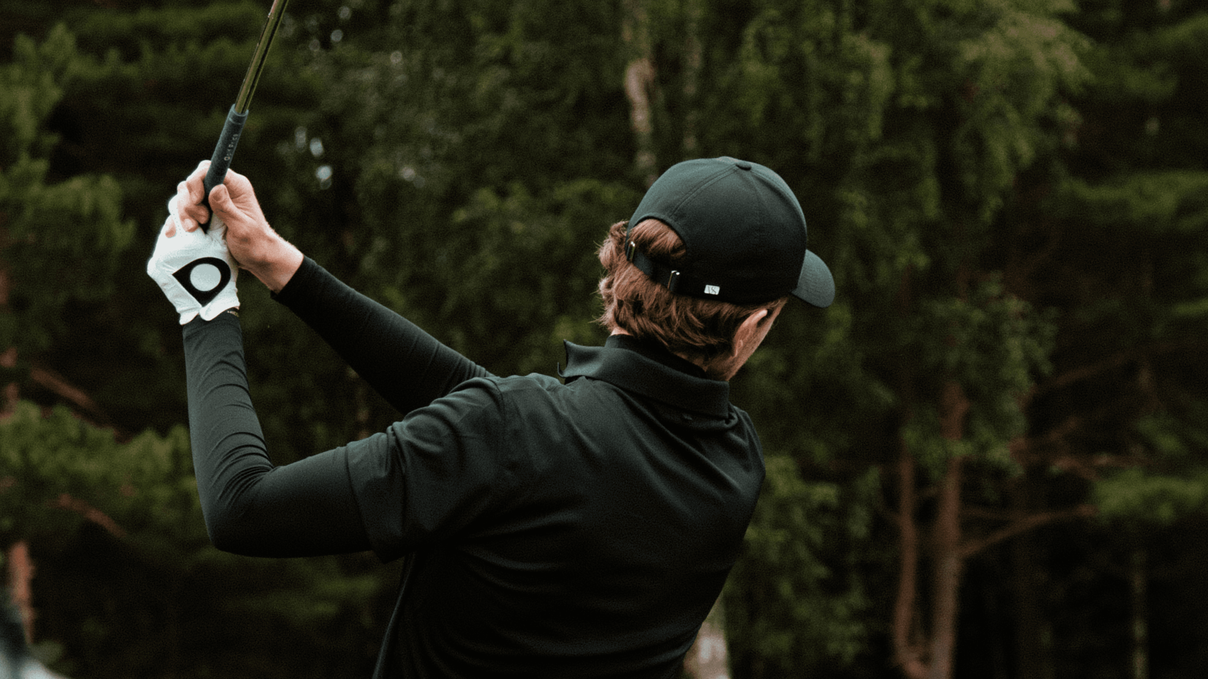Golfer wearing a black athletic sport cap from varsity headwear
