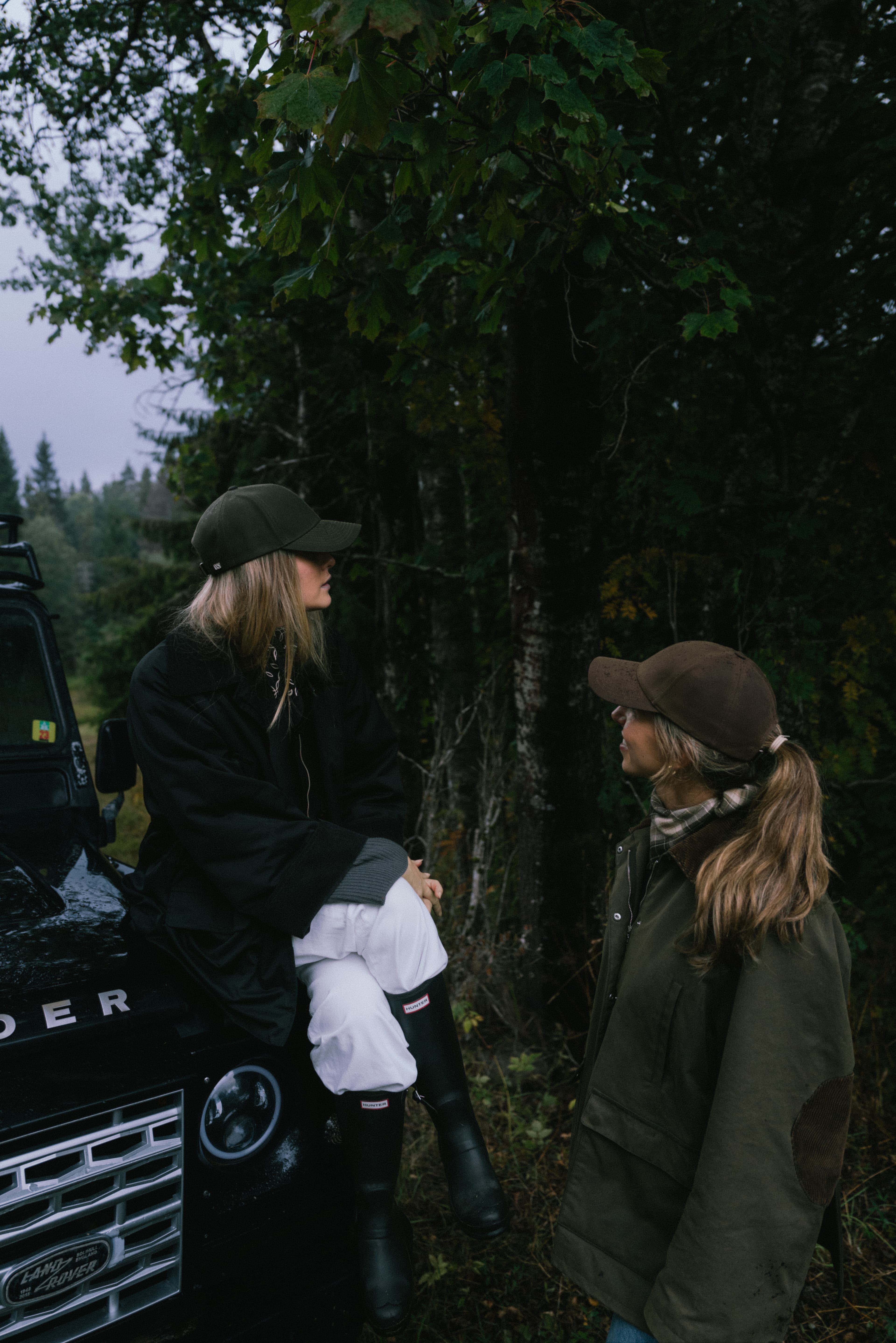 Two females wearing caps from varsity headwear in the woods